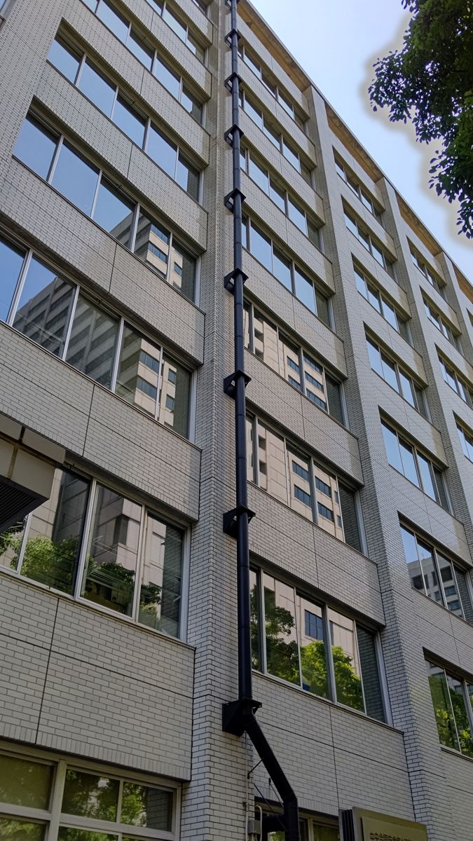 見上げた庁舎の外壁を、黒い管が上の階まで一直線に伸びている
