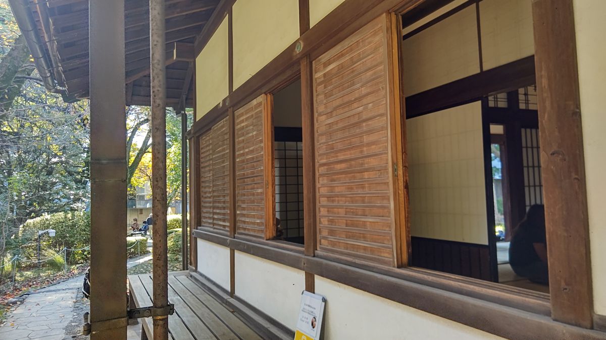 縁側に面した和風建築の外壁。木の板戸が引き開けられ、奥に障子と座敷が見える